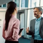 Duas pessoas em conversa de trabalho frente a frente, sem telas entre elas