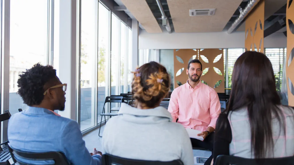 Gestor ouvindo uma integrante da equipe em conversa individual, sem papéis sobre a mesa